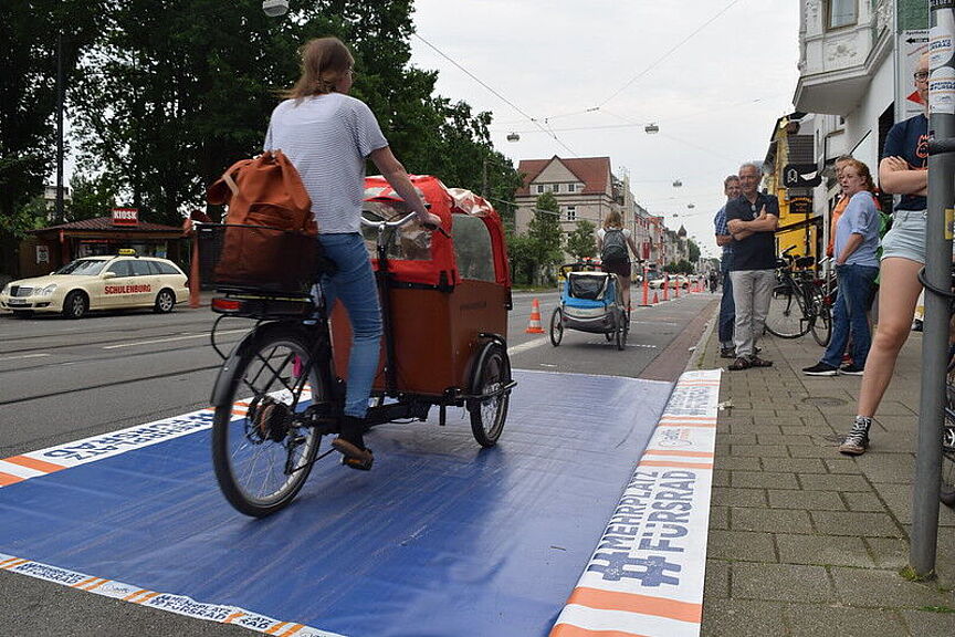 Frau von hinten fotographiert auf drei-rädrigem Latenrad auf Pop-Up-Bike-Lane