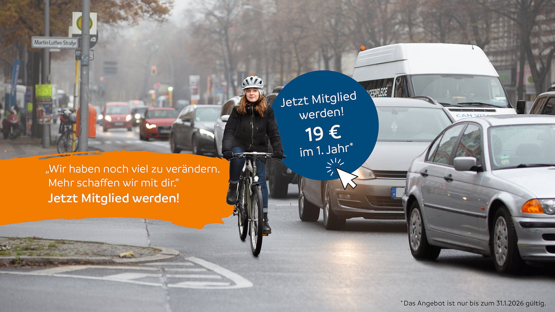 Junge Frau fährt mit dem Fahrrad durch eine befahrene Straße, umgeben von vielen Autos an einem grauen Wintertag.